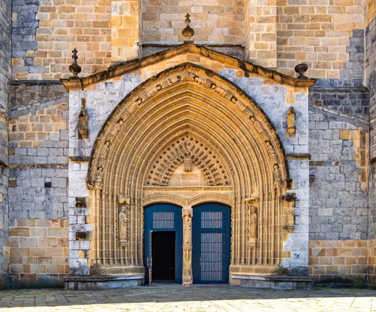 Eingangstür und Hauptfassade einer alten Steinkirche in Guernica, Baskenland, Spanien. Romanische Architektur Konzept. Religion und Glaube Konzept. Fassade eines antiken Schlosses in Europa.