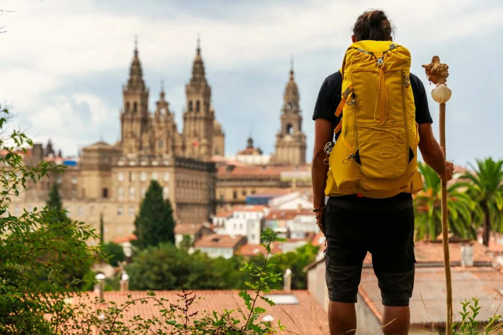 Pielgrzym patrzący na katedrę Santiago de Compostela w Hiszpanii, plecak na plecach.
