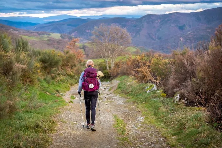 Pyhiinvaeltaja nainen vaellusvarusteiden kanssa kävelee kukkulalle O Cebreiro Galician ulkopuolella Espanjassa Pyhän Jaakobin tiellä Camino de Santiagon pyhiinvaelluspolulla.