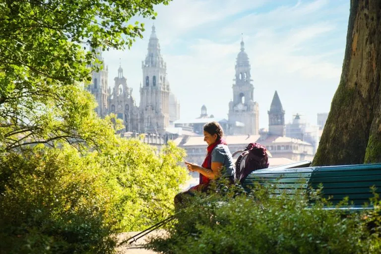 Turisti nainen pyhiinvaelluksella Santiago De Compostelassa puhelimen kanssa