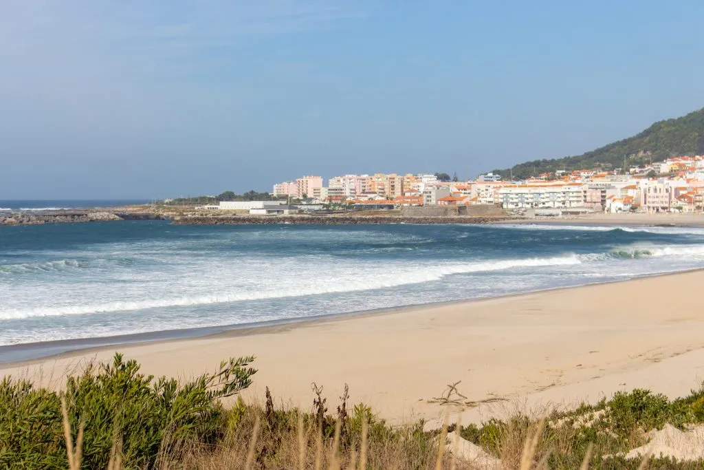 Szeroka pusta plaża z pięknymi falami i białym miastem w tle. Vila Praia de Ancora, Portugalia, punkt orientacyjny. Panoramiczne wybrzeże Oceanu Atlantyckiego ze spokojną plażą. Biały piasek na brzegu. Koncepcja podróży po Europie.